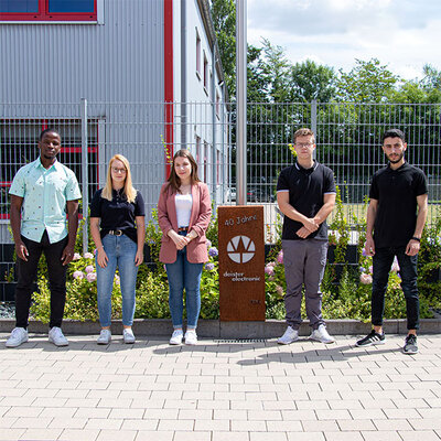 Fünf Auszubildende stehen nebeneinander draußen