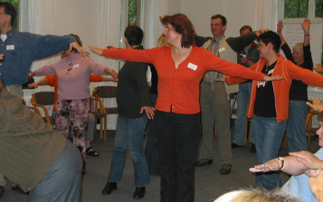 People stand in a circle and stretch out their arms