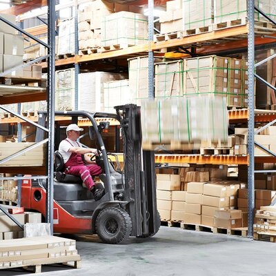 Lagerregale mit Paketen und ein Gabelstapler transportiert Pakete nach oben