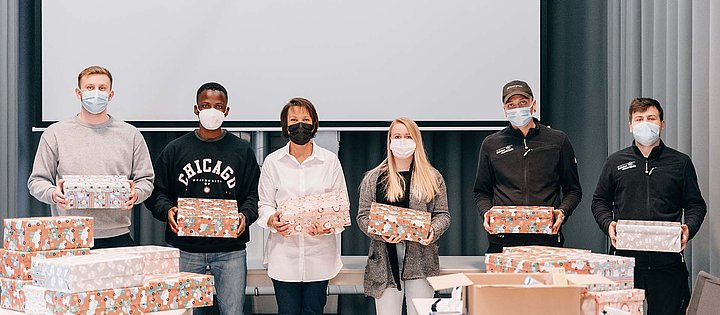 Mitarbeiter halten Schuhkartons bei der Aktion Weihnachten im Schuhkarton 2021