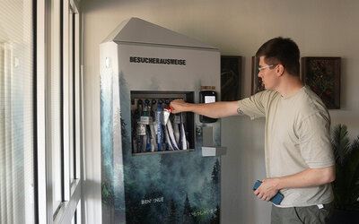 Person entnimmt Besucherausweis aus dem Obelixx