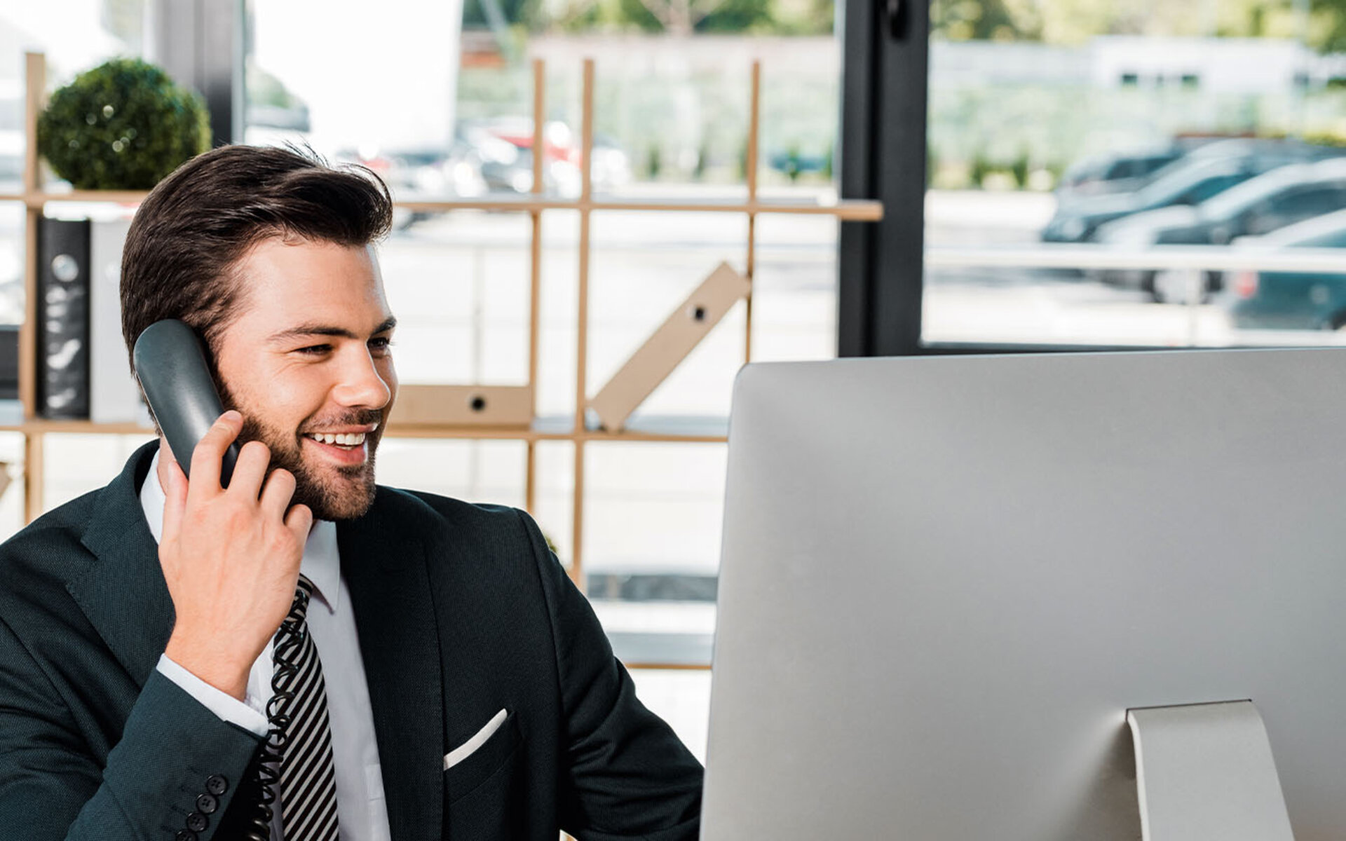 Mann an Computer sitzend und telefonierend 