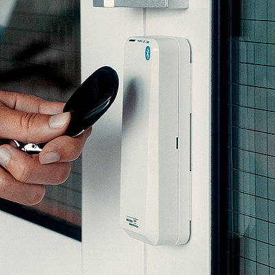 Person holds transponder in front of access control reader