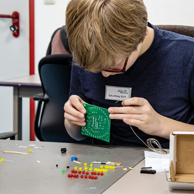 Junge lötet eine Platine am Zukunftstag bei deister electronic