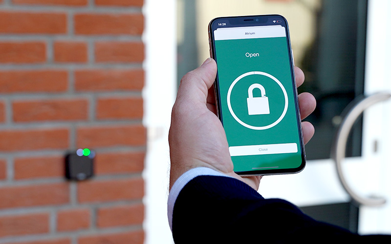 Smartphone mit deisterWallet App öffnet Tür via Bluetooth über Zutrittsleser